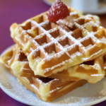 Gaufres moelleuses recette maison empilées, saupoudrées de sucre glace et garnies d’une fraise