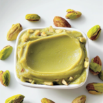 Pâte de pistache maison verte et lisse dans un bol avec pistaches entières
