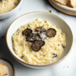 Risotto aux truffes noires servi dans une assiette avec copeaux de truffe fraîche et Parmesan râpé