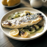 Truite au four servie avec citron rôti et légumes fondants dans une assiette blanche.