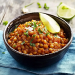 Bol de dahl de lentilles corail maison garni de coriandre fraîche et d'un quartier de citron vert, servi chaud avec une texture crémeuse et des épices parfumées.